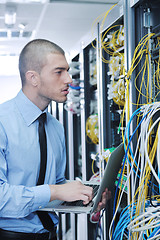 Image showing businessman with laptop in network server room