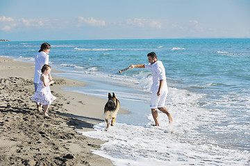 Image showing happy family playing with dog on beach