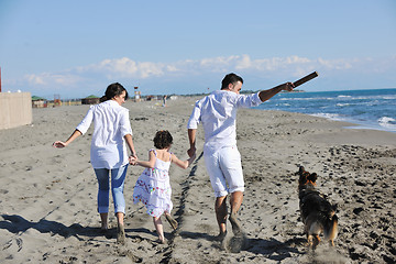 Image showing happy family playing with dog on beach