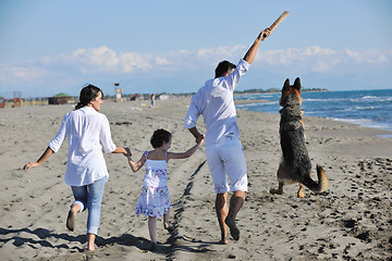 Image showing happy family playing with dog on beach