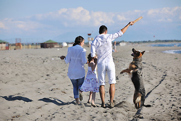 Image showing happy family playing with dog on beach