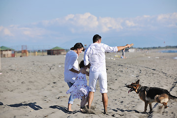 Image showing happy family playing with dog on beach