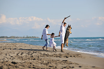 Image showing happy family playing with dog on beach