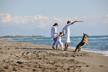 Image showing happy family playing with dog on beach