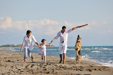 Image showing happy family playing with dog on beach