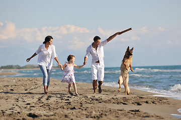 Image showing happy family playing with dog on beach