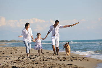 Image showing happy family playing with dog on beach