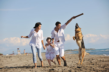 Image showing happy family playing with dog on beach