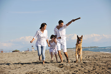 Image showing happy family playing with dog on beach