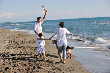 Image showing happy family playing with dog on beach