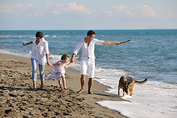 Image showing happy family playing with dog on beach