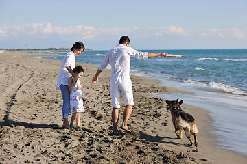 Image showing happy family playing with dog on beach