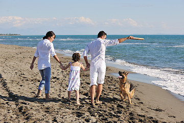 Image showing happy family playing with dog on beach