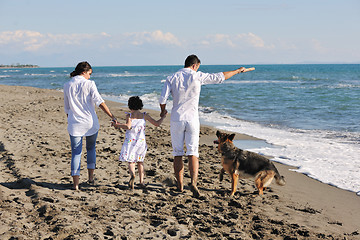 Image showing happy family playing with dog on beach