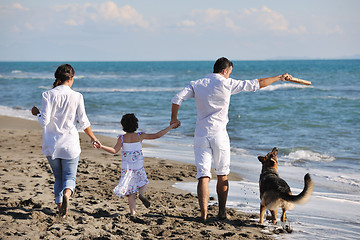 Image showing happy family playing with dog on beach