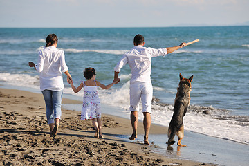 Image showing happy family playing with dog on beach