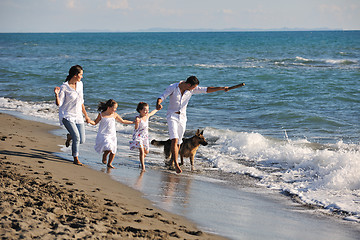 Image showing happy family playing with dog on beach