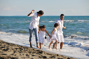 Image showing happy family playing with dog on beach