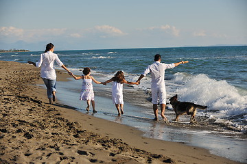 Image showing happy family playing with dog on beach