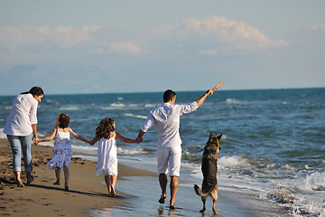 Image showing happy family playing with dog on beach