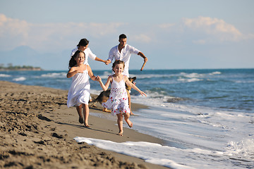 Image showing happy family playing with dog on beach