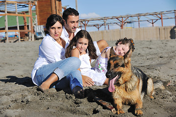 Image showing happy family playing with dog on beach