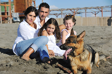 Image showing happy family playing with dog on beach