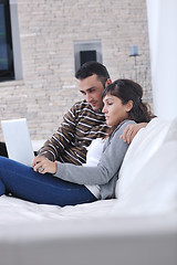 Image showing joyful couple relax and work on laptop computer at modern home