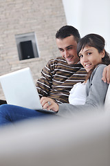 Image showing joyful couple relax and work on laptop computer at modern home