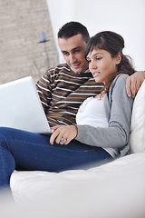 Image showing joyful couple relax and work on laptop computer at modern home