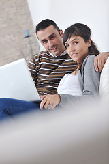 Image showing joyful couple relax and work on laptop computer at modern home