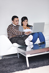 Image showing joyful couple relax and work on laptop computer at modern home