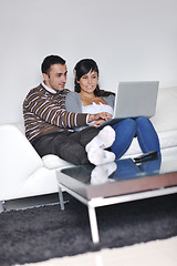 Image showing joyful couple relax and work on laptop computer at modern home