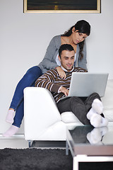 Image showing joyful couple relax and work on laptop computer at modern home