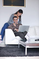 Image showing joyful couple relax and work on laptop computer at modern home