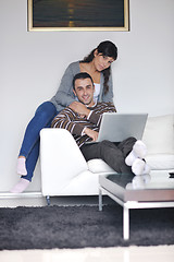 Image showing joyful couple relax and work on laptop computer at modern home