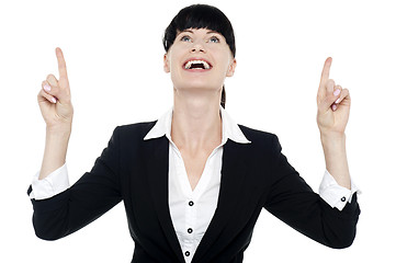 Image showing Excited businesswoman looking ad pointing upwards