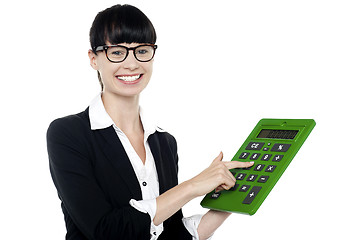 Image showing Bespectacled woman using big green calculator