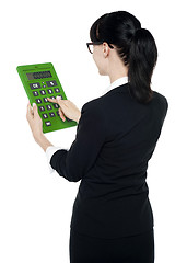 Image showing Rear view of corporate woman using green calculator