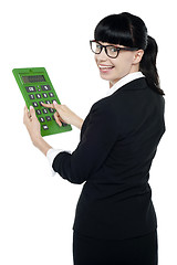 Image showing Bespectacled woman turning back, holding calculator