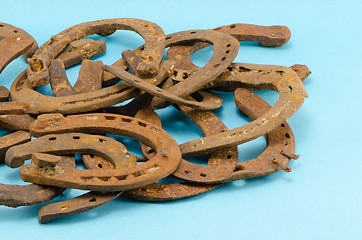 Image showing stack of old retro horse shoes on blue 