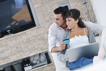 Image showing joyful couple relax and work on laptop computer at modern home