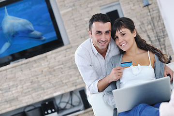 Image showing joyful couple relax and work on laptop computer at modern home