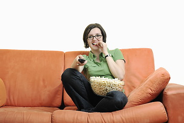 Image showing young woman eat popcorn on orange sofa