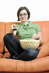 Image showing young woman eat popcorn on orange sofa