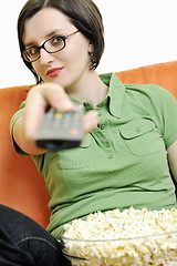 Image showing young woman eat popcorn on orange sofa