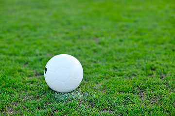 Image showing Soccer ball on grass at goal and stadium in background