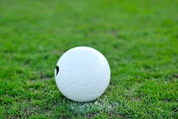 Image showing Soccer ball on grass at goal and stadium in background