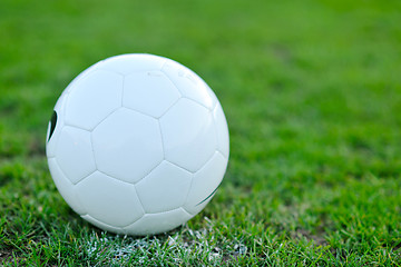 Image showing Soccer ball on grass at goal and stadium in background