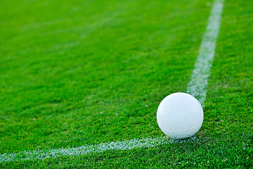 Image showing Soccer ball on grass at goal and stadium in background